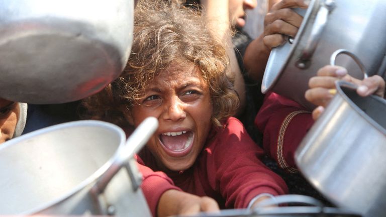 Dítě se pokouší získat přístup k jídlu z charitativní kuchyně v Khan Younis. Pic: Reuters