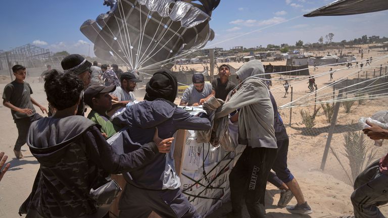 Palestinci spěchají, aby sbírali humanitární pomoc airdropped od padáků do Deir al-Balah, Central Gaza Strip, úterý 5. srpna 2025 (AP Photo/Abdel Kareem Hana)