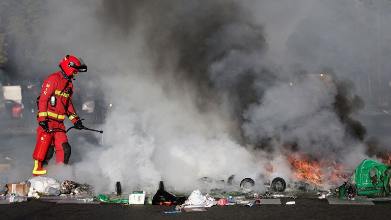 Francouzský hasič uhasí hořící koše a předměty nastavené studenty. Pic: Ap