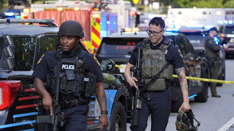 Ozbrojení policisté chodí poblíž scény natáčení na CDC. Pic: Ap