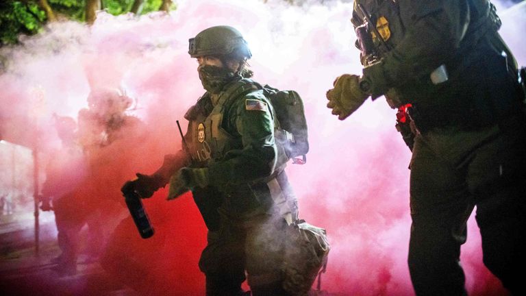 Policejní a federální důstojníci házejí plynové kanystry, aby v neděli rozptýlili davy protestující proti imigračním zásahům v Portlandu. Pic: Ap
