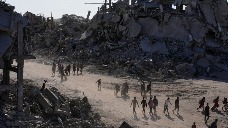 Přemístění Palestinci procházejí kolem zničených budov ve městě Gazy. Pic: Ap